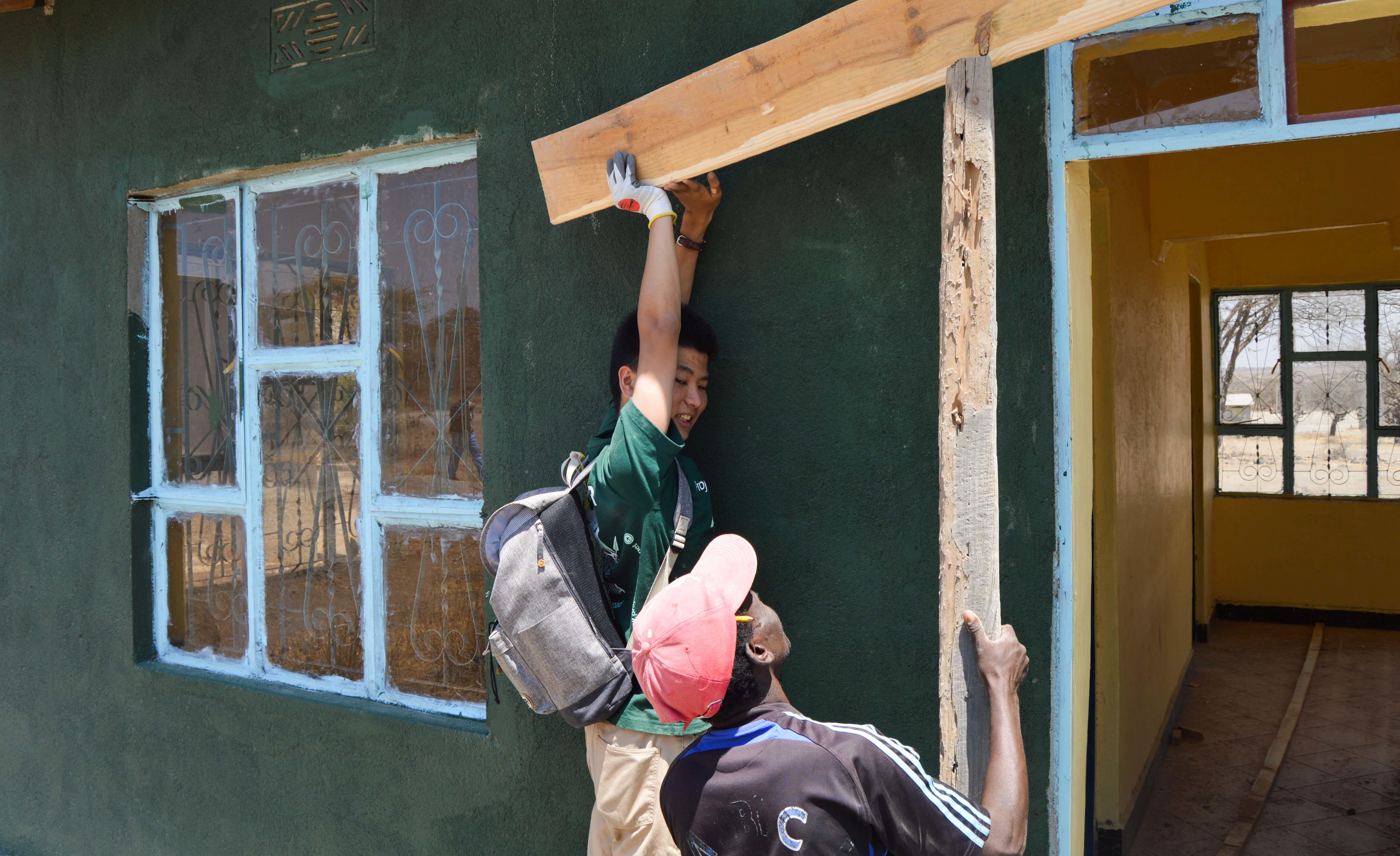 Male Projects Abroad Community volunteer helps build a house for teachers in a school during his Community Volunteer Work in Tanzania. Male Culture and Community Volunteer helps build a house for teachers at a school holding a peice of wood during a volunteering project in Tanzania.